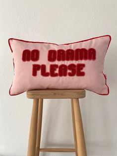 a pink pillow that says no drama please on the front and red lettering on the back