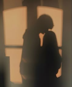 the shadow of a person standing in front of a window talking on a cell phone