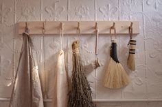 four brooms hanging on a wall and two are hung from the hooks in front of them