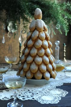 a christmas tree made out of cookies sitting on a table with wine glasses and pine branches