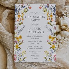 a white graduation party card with colorful flowers and leaves on it next to a flower bouquet