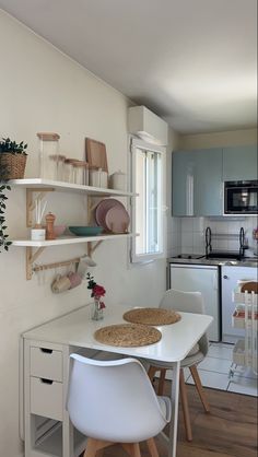 a small kitchen with white appliances and wooden flooring, including a dinning table