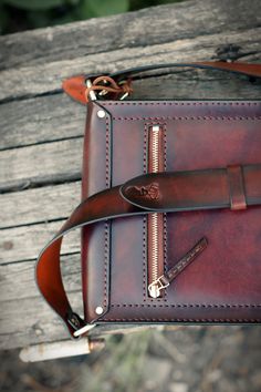 a brown leather bag sitting on top of a wooden bench