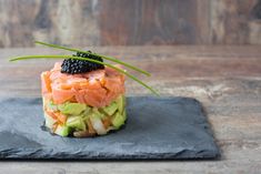 a black plate topped with food on top of a wooden table