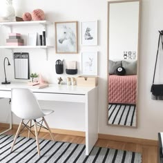 a desk with a mirror, chair and pictures on the wall above it in a room