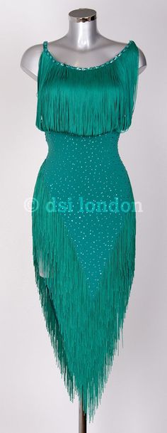 a green dress with fringes and beads on the bottom is displayed in front of a mannequin's head