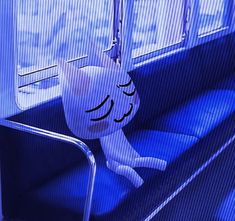 a stuffed animal sitting on top of a blue seat next to a metal rail and window