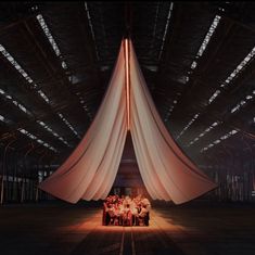 a group of people sitting at a table under a large white cloth covered structure in an industrial building