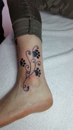 a woman's foot with a tattoo on it that has paw prints in the shape of hearts