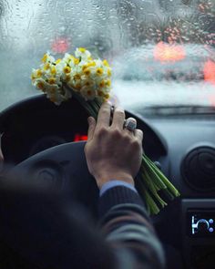 a person holding flowers while driving in the rain