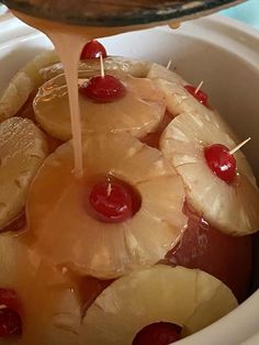 someone is pouring pineapple syrup into a crock pot filled with bananas and cherries