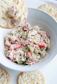 a white bowl filled with crab salad next to crackers