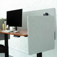 an office cubicle with two computer monitors and a keyboard on the desk, in front of a white brick wall