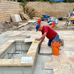 a man in red shirt and blue jeans working on a concrete slab with cement pavers