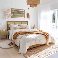 a bedroom with white walls and wooden floors has a large bed covered in beige blankets