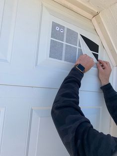 a man is painting the side of a white garage door with black tape and scissors