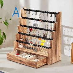 a wooden jewelry organizer on a table next to a potted plant