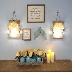 three mason jars with flowers in them are on a table next to candles and framed pictures