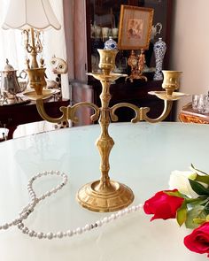 a white table topped with a gold candelabra next to a red rose