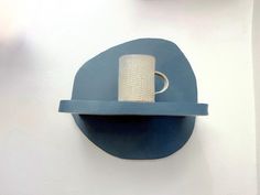 a blue shelf with a roll of toilet paper on it and a cup in the middle