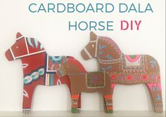 two wooden horses standing next to each other on top of a white shelf with the words cardboard dala horse diy