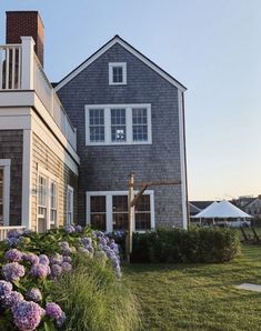 a house with purple flowers in the front yard