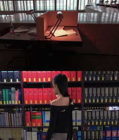 a woman standing in front of a bookshelf filled with binders and folders