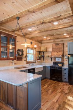 a large kitchen with an island in the middle and wood flooring on the walls