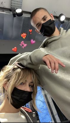 a man and woman wearing face masks in front of a mirror with hearts on it