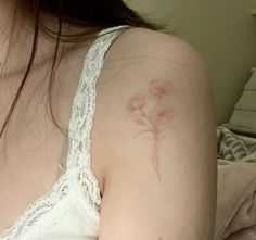 a close up of a person with a flower tattoo on their left arm and shoulder