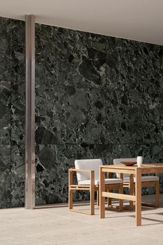 a table and two chairs sitting in front of a wall with black marble on it