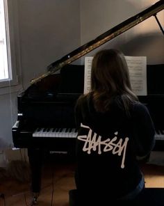 a woman sitting at a piano in front of a window