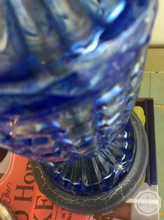 a blue glass vase sitting on top of a table next to some books and pens