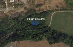 an aerial view of a park with a blue lake in the middle and do not go alone written on it