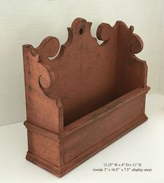 an old wooden shelf with decorative carvings on the top and bottom, sitting on a white surface