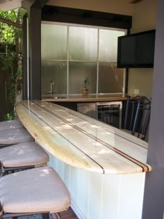 an outdoor bar with several stools and a television mounted on the wall behind it