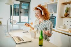 a woman sitting at a kitchen counter with a laptop and cup in front of her