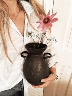 a woman holding a vase with flowers in it