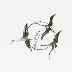 three metal birds flying in the air with their wings spread out to form a circle