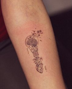 a tattoo on the arm of a woman with a light bulb and flowers in it