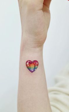 a woman's arm with a heart shaped tattoo on the left side of her wrist