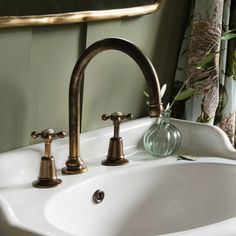 a bathroom sink with two faucets and a vase on the counter next to it