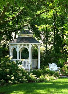 a white gazebo sitting in the middle of a lush green park