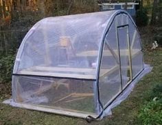 a small greenhouse in the middle of some grass