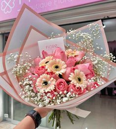 a bouquet of pink roses and baby's breath is held in front of a store