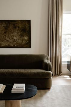 a living room filled with furniture and a painting hanging on the wall above a coffee table