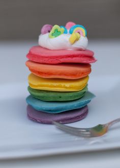 a stack of colorful donuts sitting on top of each other next to a fork