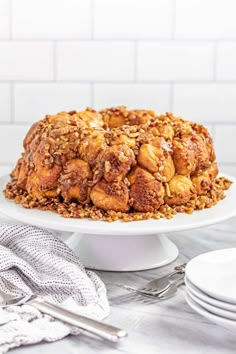 a white plate topped with a cake covered in nuts and crumbs on top of a table