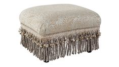 an ottoman with tassels and beads on the bottom, sitting in front of a white background