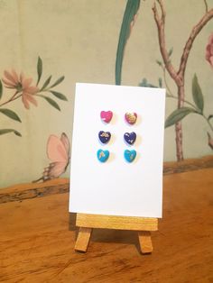 three heart shaped studs sitting on top of a wooden easel next to a painting